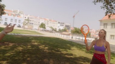 İki arkadaş güneşli bir günde parkta frizbi oynayarak dostluk ve açık hava eğlencesi sergileyerek eğleniyorlar..