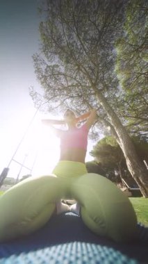 Açık havada yoga yapan zinde bir birey, güneşli bir ortamda esneklik ve canlı giysiler sergiliyor..