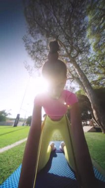 Genç bir kadın yoga minderinin üzerinde bir dizi dinamik esneme hareketi yapıyor, güzel bir parkta güneş ışığının tadını çıkarıyor.