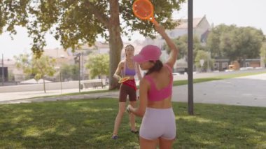 İki arkadaş neşeli ve enerjik bir oyunun keyfini çıkarıyorlar. Canlı bir güneş ışığı parkı ortamında.