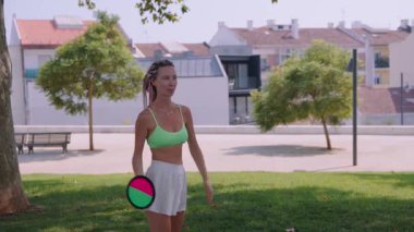 Neşeli ve hayat dolu bir kadın güneşli bir parkta eğlenceli bir oyun oynamaktan zevk alıyor, hareketli ve aktif bir yaşam tarzı sergiliyor.