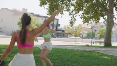 İki hevesli arkadaş güneşli parkta renkli raketleriyle eğlenceli bir oyun oynuyorlar, birlikte vakit geçiriyorlar.