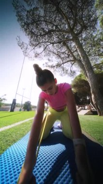 Genç bir insan, sakin ve sakin bir açık havada paspasın üzerinde çeşitli yoga pozları veriyor.