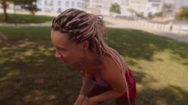 Neşeli ve hayat dolu bir sahne. Güneşli parkta tenis raketiyle oynayan genç bir kadın.