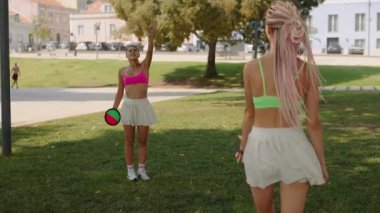 İki yakın arkadaş, heyecanlı ve enerjik, güneşli bir günün tadını çıkarıyorlar. Parkta renkli spor kıyafetleriyle oyunlar oynuyorlar.