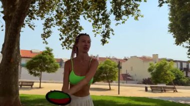 Neşeli ve hayat dolu bir yaz sahnesi. Güneşli bir park ortamında frizbi oynayan bir kadın.