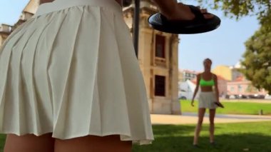 Sıcak ve güneşli bir günde, iki kadın raket sporlarından ve canlı, canlı bir parkta eğlenmekten zevk alır.