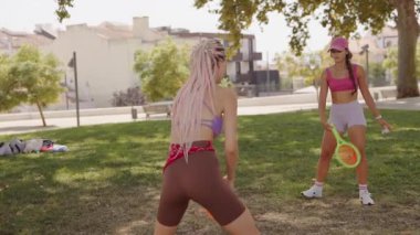 İki kadın parkta neşeli ve eğlenceli bir oyun oynuyorlar, atletizm ve açık havada arkadaşlıklarını sergiliyorlar.