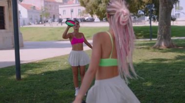 İki enerjik kadın güneşli parkta spor yaparak eğleniyorlar. Spor ve arkadaşlığı teşvik ediyorlar..