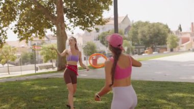 İki genç kadın parkta eğleniyorlar. Formlarını ve dostluklarını gösteriyorlar.