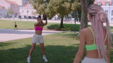 İki neşeli kadın parkta güneşli bir günün tadını çıkarıyorlar. Eğlenceli bir aktiviteye katılıyorlar, renkli kıyafetler giyiyorlar.