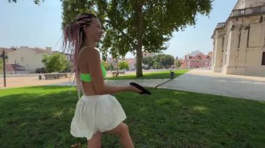 İki kadın coşkuyla açık havada bir oyun oynuyorlar, parkta atletizm ve neşelerini sergiliyorlar.