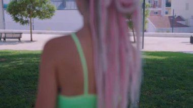 İki neşeli kız güneşli bir parkta renkli bir kürekle oynayarak neşe ve dostluk gösterisi yapıyorlar.