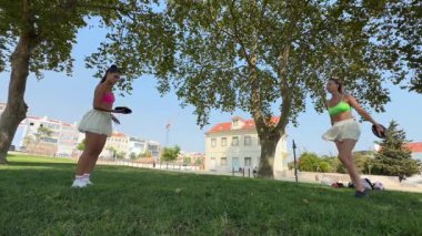 Güneşli bir parkta, iki kadın hareketli yaşam tarzlarını sergileyerek canlandırıcı bir fitness rutinine girişir.