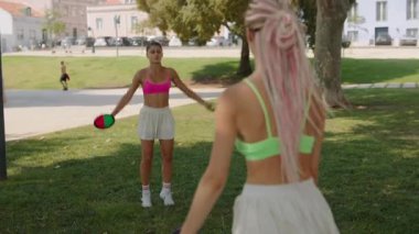 İki neşeli kadın güneşli bir günün tadını çıkarıyor. Parkta renkli frizbilerle eğlenceli bir oyun oynuyorlar.