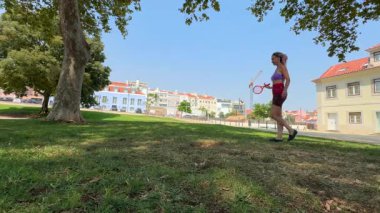 İki kız güzel, güneşli bir günün tadını çıkarırken güzel bir park ortamında çimlerin üzerinde tenis oynuyorlar.