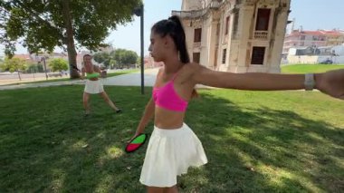 Güzel bir parkta, iki kadın neşeli ve enerjik bir dans eder, birlikte neşeli hareketlerini sergilerler.