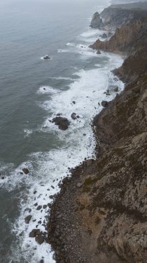Engebeli bir kıyı şeridi boyunca dalgaları çarpıştıran nefes kesici hava manzaraları, güzelliğin vücut bulmuş hali.