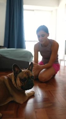 Sıcak ve davetkar bir mekanda, bir kadın sevimli Fransız Bulldog 'uyla sevgi dolu bir etkileşimi paylaşıyor.