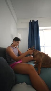 Bir kadın, kanepede birlikte otururken sevgili köpeğiyle mutlu ve neşeli bir anın tadını çıkarır.