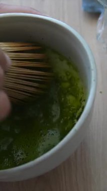 Yakından bakınca bambu çırpıcılı bir kasede etkin bir şekilde eşleşen yeşil çayı çırpma sanatını görüyoruz.