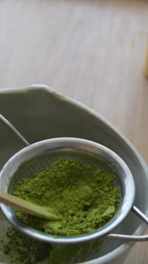 Dikkatlice kibrit tozu hazırlamak, canlı yeşil özü vurgulamak, modern bir mutfakta kullanılan aletlerle birlikte.