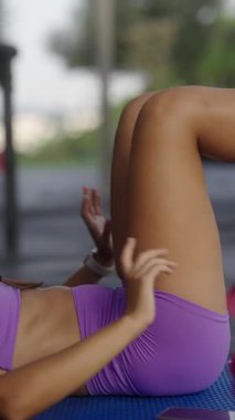 Bir kadın açık havada zorlu bir antrenmana katılıyor. Parlak spor kıyafetleriyle atletizmini gösteriyor.