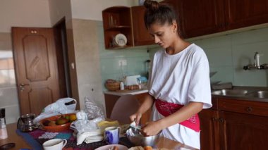 Bir kadın ev yemeği yapar, mutfak yeteneklerini açık bir mutfakta taze malzemelerle sergiler..