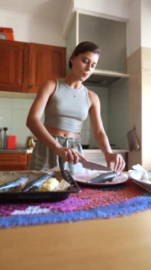 Şık ve modern bir mutfakta, genç bir kadın özenle hazırlanmış bir tabakta balığı hazırlıyor.