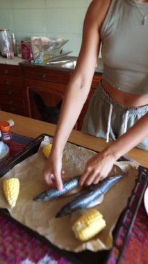 Bir birey, parlak bir mutfakta nefis bir yemek için renkli mısırlı taze balığı ustalıkla düzenler.