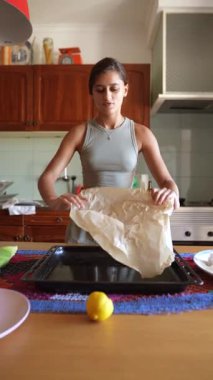 Samimi bir mutfakta, genç bir kadın, limon ve işlemden etkilenen meraklı bir köpek gibi hamuru hazırlar.