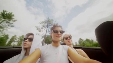 Üç arkadaş güneşli bir günün tadını çıkarırlar, üstü açık bir arabada keyifle dolaşırlar ve keyifli anları yakalarlar.