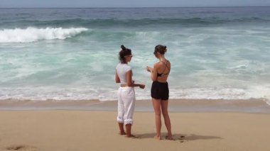 Dostlar güler ve sohbet eder güzel bir sahilde Dalgalar çarpar, birlikte neşeli bir anı yakalar