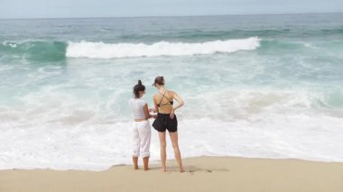 İki kadın, yaz eğlencesinin esansını yakalayan güzel bir sahilde neşeyle oynuyorlar.