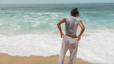 Canlı ve canlı bir plaj sahnesi yetenekli bir dansçının dalgaların yanında zarifçe performansını sergiliyor.
