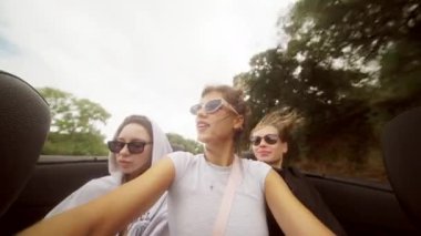 Üç neşeli arkadaş bulutlu ama güzel bir günde üstü açık arabalarıyla kaygısız bir gezinti yapıyorlar.