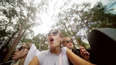 Eğlenceli bir grup arkadaş üstü açık bir arabada kaygısız bir yolculuğun tadını çıkarıyor, gülüyor ve anılar yaratıyorlar.