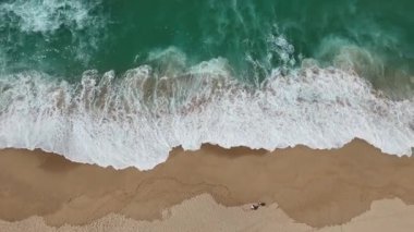 Hava sineması kumlu bir plaja çarpan büyüleyici dalgaları gösteriyor. Doğa meraklıları için mükemmel bir görüntü.