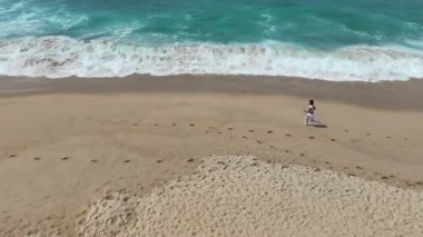 Huzurlu ve sakin bir sahne. Kumlu bir plajda rahatça yürüyüp okyanus esintisinin tadını çıkaran bir insan.