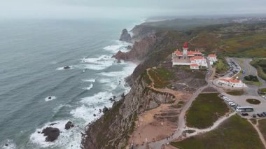 Nefes kesici bir hava manzarası çarpan dalgaların ortasında bir deniz fenerinin yer aldığı çarpıcı kayalık bir kıyı şeridini gözler önüne seriyor.