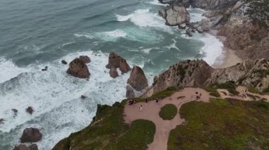 Burada çarpan dalgalar ve manzaralı yollarla tamamlanmış kayalık bir kıyı şeridinin nefes kesici ve çarpıcı bir görüntüsü var.
