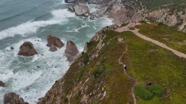 Çarpışan dalgaların yürüyüş yollarıyla buluştuğu engebeli kıyı uçurumlarının nefes kesici bir hava perspektifini tecrübe edin.