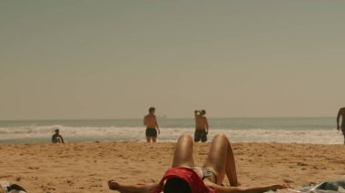 Sıcak güneşin ve dalgaların tadını çıkaran canlı bir plaj sahnesi, yaz havası ve rahatlama için ideal.