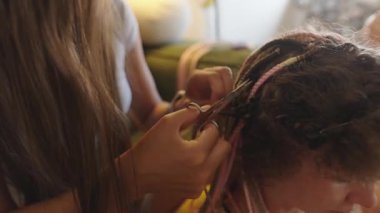 Renkli uzantılar ve karmaşık teknikler içeren heyecan verici ve canlı bir saç örme seansına katılın.