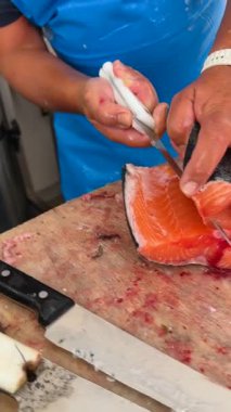 Çok yetenekli bir aşçı ustalıkla taze somon kesiyor, olağanüstü bir hassasiyet ve mutfak uzmanlığı sergiliyor.