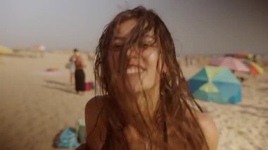 Canlı ve hayat dolu bir plaj sahnesi genç bir kadını keyifle yaz havasını kutluyor.