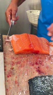 Becerikli bir aşçıyı izleyin taze somon filetosu, deniz ürünleri hazırlama ve zanaat sanatını sergiliyor.