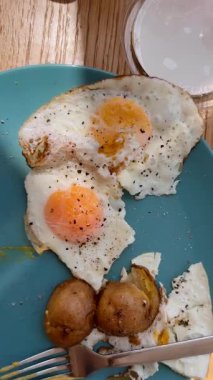 Canlı yumurtalar, taze sebzeler ve kırsal ahşap bir masaya yayılmış renkli bir kahvaltı.