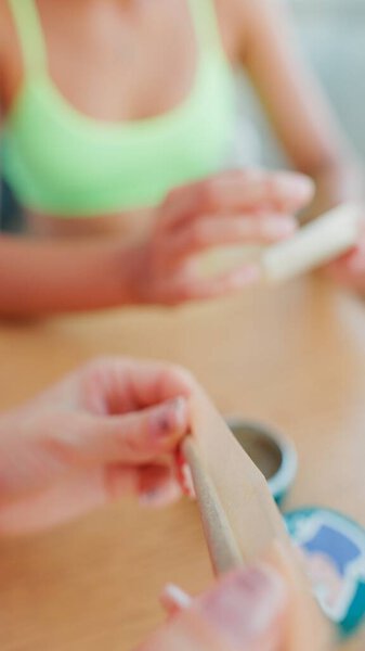 Hands prepare rolling paper in a serene setting, fostering relaxation and creativity for all involved