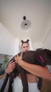 Neşeli ve renkli bir mutfakta neşeli genç bir kadın neşeli köpeğiyle güzel vakit geçirmekten mutlu olur.